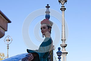Beautiful young woman with typical green frilly dress and dancing flamenco in plaza de espana in sevilla, andalusia, she is on a photo
