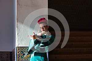 Beautiful young woman in typical green frilly dress dancing flamenco in plaza de espana in seville, andalusia. She makes a photo