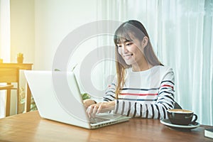 Beautiful young woman typing on laptop computer