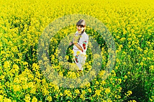 Beautiful young woman in Ukrainian embroidered standing in a field of yellow flowers