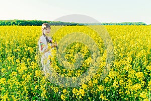 Beautiful young woman in Ukrainian embroidered standing in a field of yellow flowers