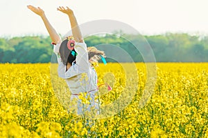 Beautiful young woman in Ukrainian embroidered standing in a field of yellow flowers.back view