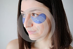 Beautiful young woman with under eye patches. Face skin care and beauty treatment concept. Closeup portrait