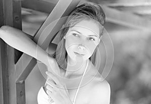 Beautiful young woman under wooden pier on beach.