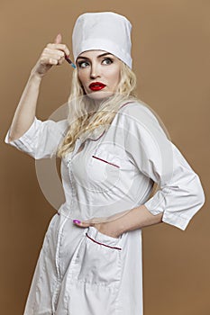 A beautiful young woman in the uniform of a nurse with a syringe in her hand. Sexy blonde with red lips. Compulsory vaccination.