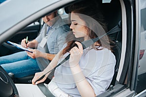 Beautiful young woman upset with results of driving tests. Strict examiner holds clipboard and makes notes of her