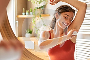 Happy young woman using roll on deodorant