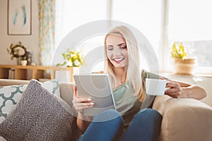 Beautiful young woman using digital tablet at home