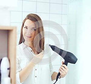 Beautiful young woman  using hair dryer drying hair. Hair care