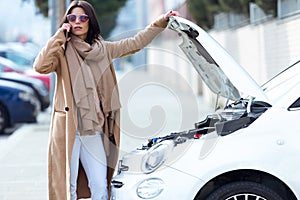 Beautiful young woman using her mobile phone calls for assistance for car.