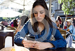 Beautiful young woman using her mobile phone in the street.