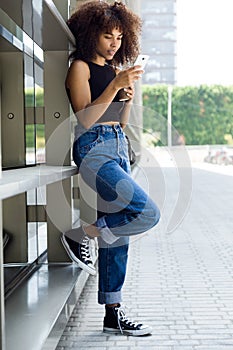 Beautiful young woman using her mobile phone in the street.