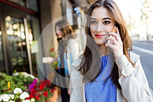 Beautiful young woman using her mobile phone in the street.