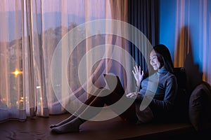 A beautiful young woman using laptop computer for video call with bright light screen in the late night at home