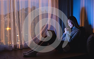 A beautiful young woman using laptop computer for video call with bright light screen in the late night at home