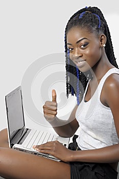 Beautiful young woman using a laptop showing thumb up