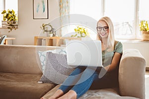 Beautiful young woman using laptop on sofa at home