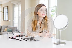 Beautiful young woman using make up cosmetics looking to side, relax profile pose with natural face with confident smile