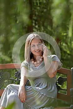 Beautiful young woman using mobile phone on park bench