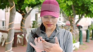 Beautiful young woman using a phone and browsing online on an app while standing in an urban city alone. One trendy and