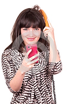 Beautiful young woman using retro orange and mobile phone telephone