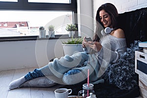 Beautiful young woman using smart phone at home in the morning