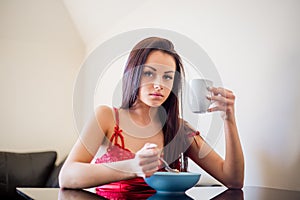 Beautiful young woman using smartphone while having a healthy breakfast a