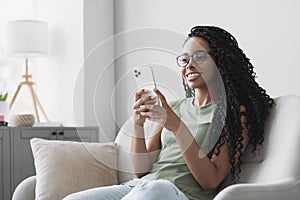 Beautiful young woman using smartphone at home. Mixed race girl looking at mobile phone.