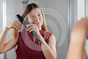 Bellissimo giovane donna vapore piastra per capelli sul stile capelli sul Specchio sul il bagno 