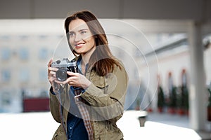 Beautiful young woman using vintage photo camera on the railway station platform.