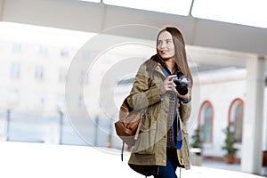 Beautiful young woman using vintage photo camera on the railway station platform.