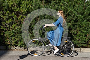 Beautiful young woman and vintage bicycle, summer. Red hair girl riding the old black retro bike outside in the park.