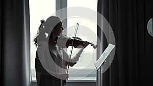 Beautiful young woman violinist plays the violin at home