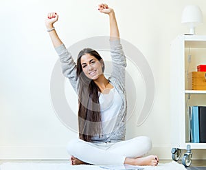 Beautiful young woman waking up and stretching arms at home.