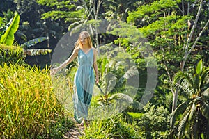 Beautiful young woman walk at typical Asian hillside with rice farming, mountain shape green cascade rice field terraces