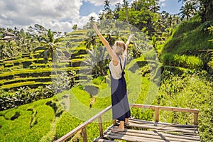 Beautiful young woman walk at typical Asian hillside with rice farming, mountain shape green cascade rice field terraces