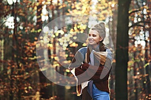 Beautiful young woman walking in the autumn forest