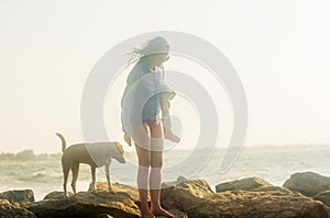 Beautiful young woman walking with the dog on the beach