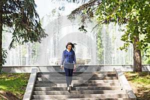 Beautiful young woman walking in green summer park