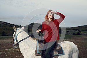 Beautiful young woman walking with her horse in the mountains outdoors