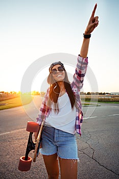 Beautiful Young woman walking and holding a skateboard