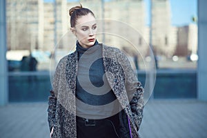 Beautiful young woman walking at the mirrored window of city mall