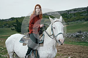 Beautiful young woman walking in the mountains with her horse