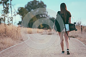 Beautiful young woman walking to the institute with skateboard and backpack