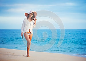 Beautiful young woman walking on tropical beach