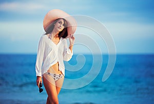 Beautiful young woman walking on tropical beach