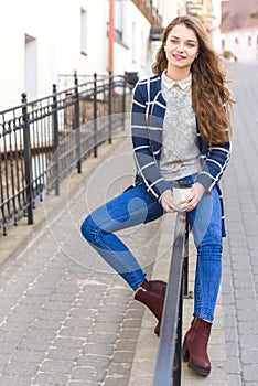 Beautiful young woman walks in city and drinks coffee