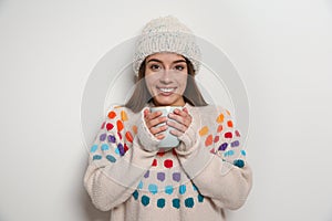 Beautiful young woman in warm sweater with cup of hot drink