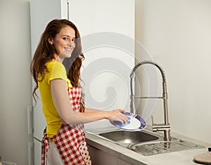 Beautiful young woman wash dishes in the kictchen
