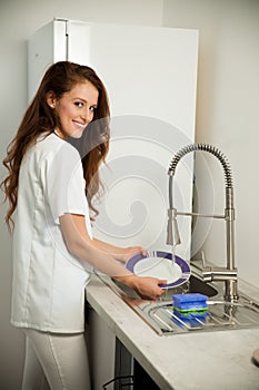 Beautiful young woman wash dishes in the kictchen